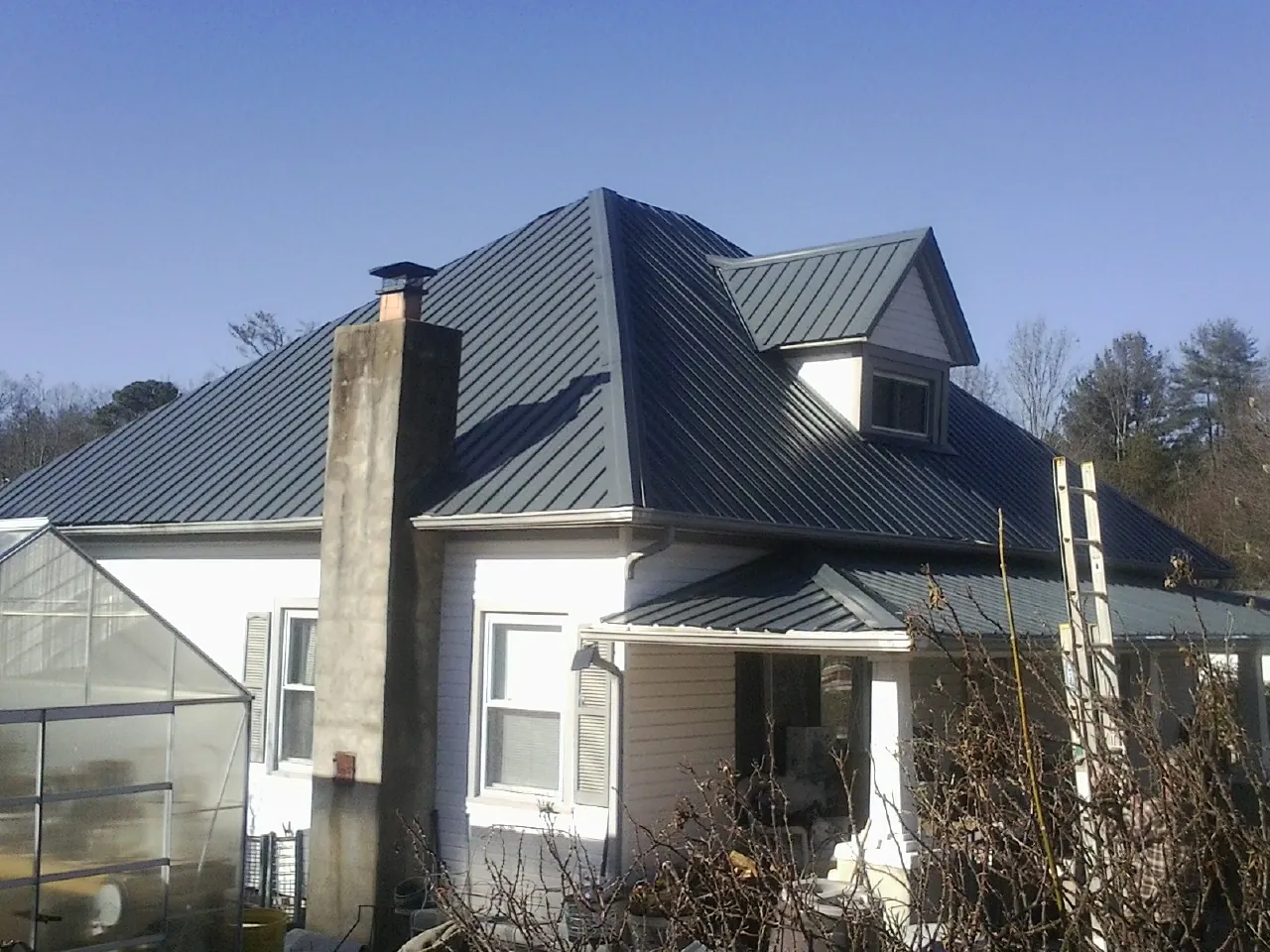 Dark blue standing seam metal roof on a white farmhouse with dormer — Slate & Tile Roof Repair by Roofing Brothers in Brecksville