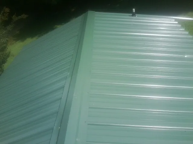 New green metal panels meeting at the ridge of a roof — Flat Roof Repair work by our crew in Brecksville
