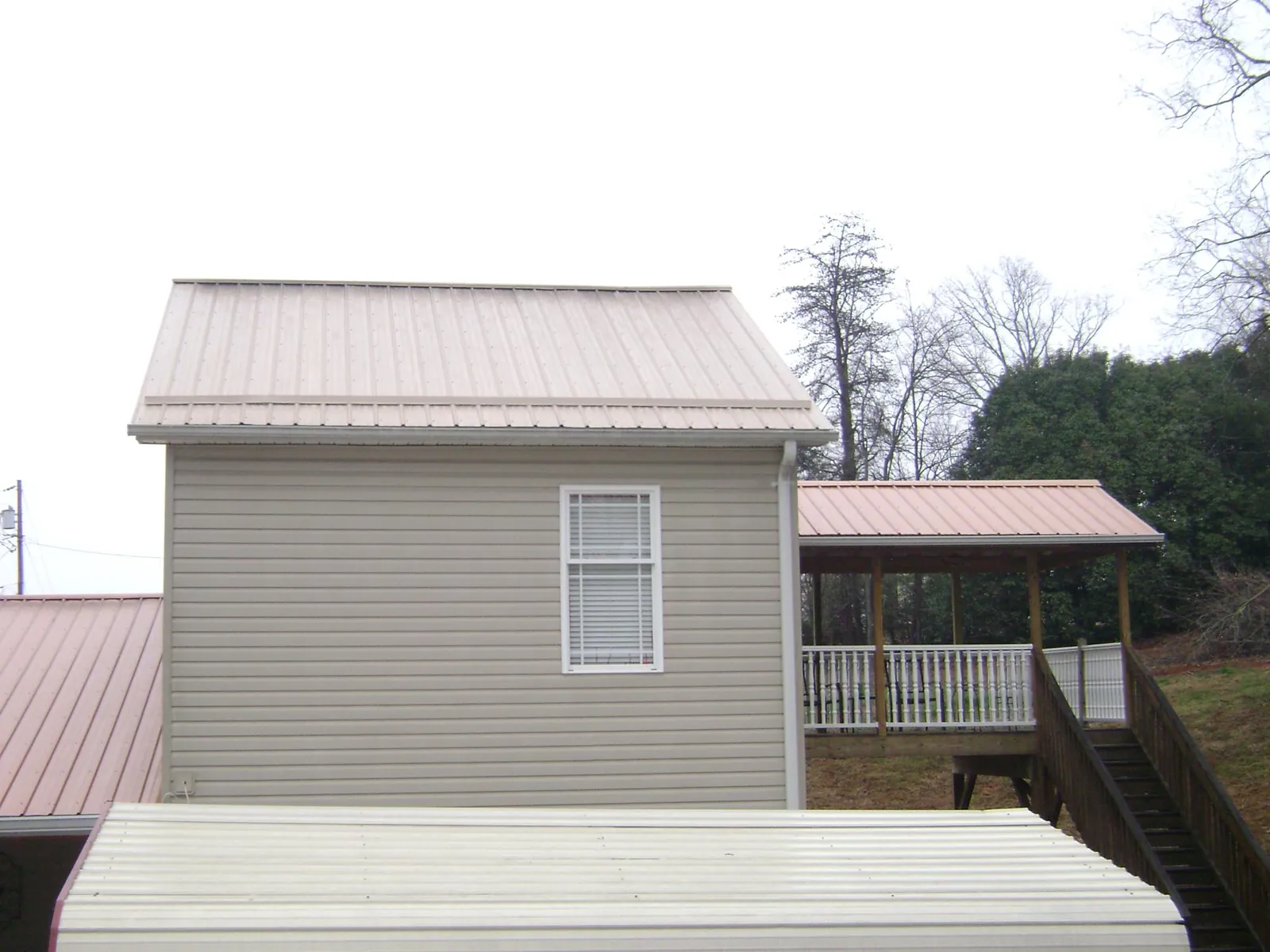 Tan metal roofs on a two story addition and attached porch, from a Roof Replacement job in Brecksville