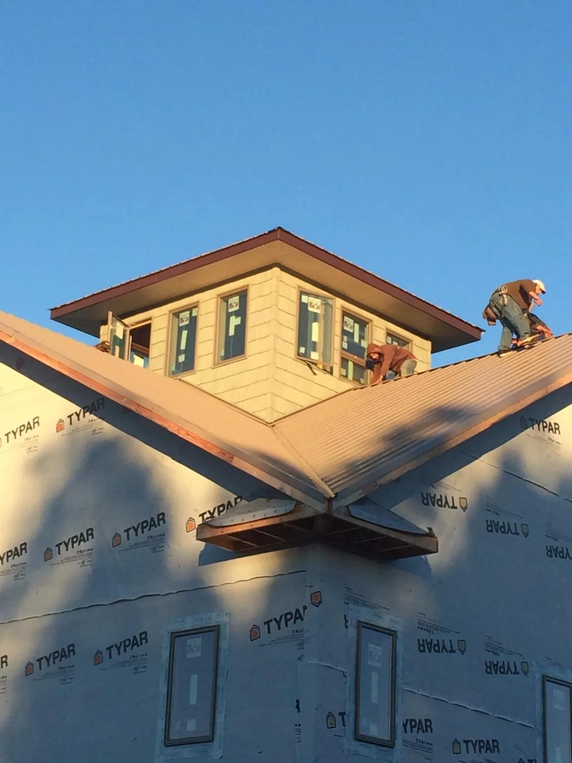 Roofers working around a rooftop cupola on a new metal roof at sunset — Roof Waterproofing in Brecksville by Roofing Brothers